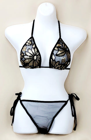 Black sheer embellished bikini set on a mannequin, featuring a triangle top with gold sparkly embellishments and tie-side bottoms.